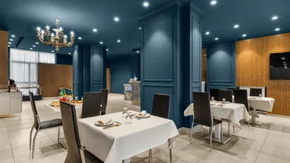 Hotel Regina Caserta · 4 stelle · A due passi dalla Reggia Sala da pranzo elegante con pareti blu e tavoli apparecchiati con tovaglie bianche