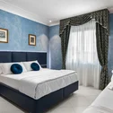Hotel Regina Caserta · 4 stelle · A due passi dalla Reggia Camera da letto con letto matrimoniale, pareti azzurre e tende decorate