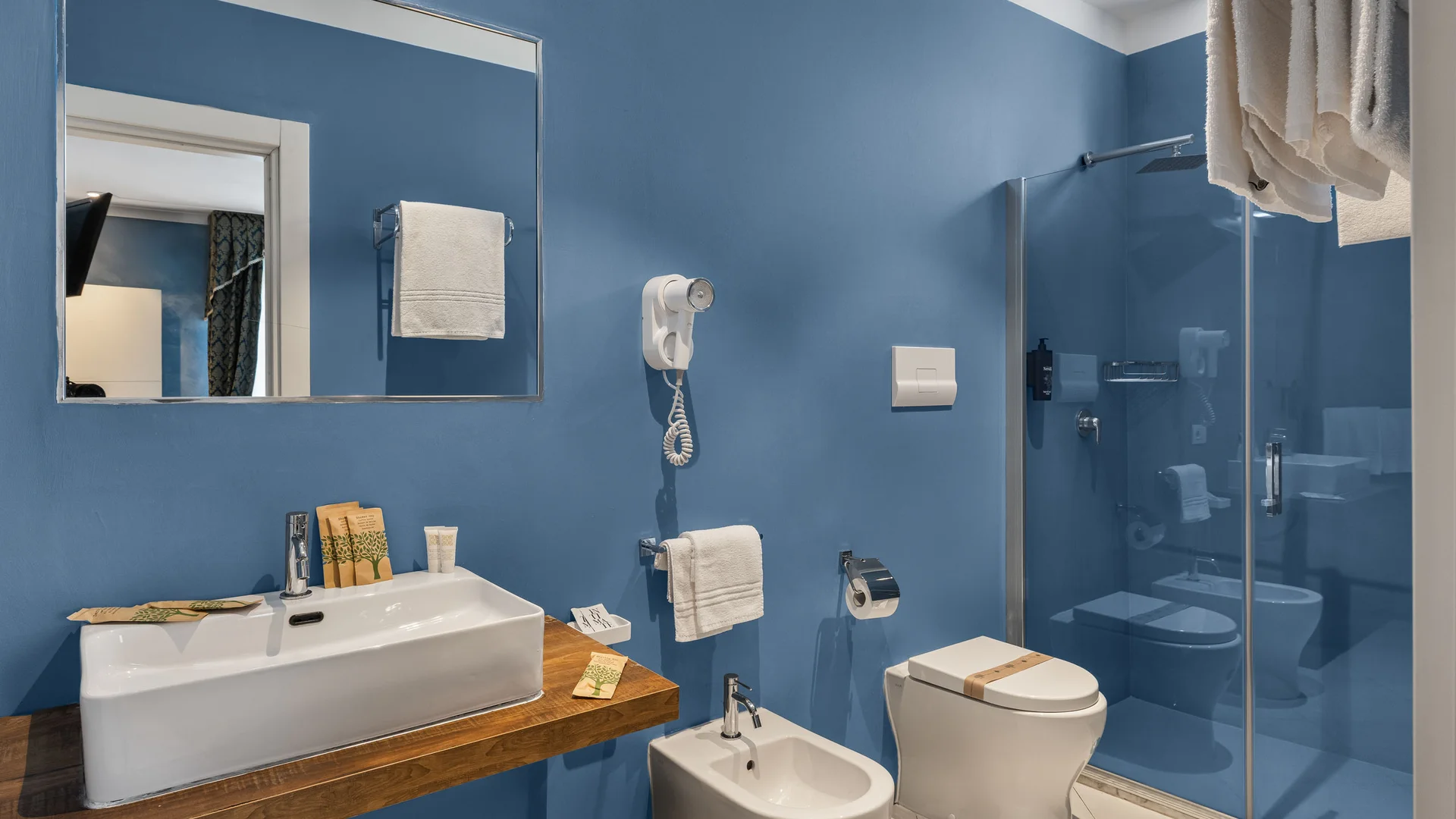 Hotel Regina Caserta · 4 stelle · A due passi dalla Reggia Bagno moderno con pareti blu, lavabo, bidet, WC e doccia con parete in vetro