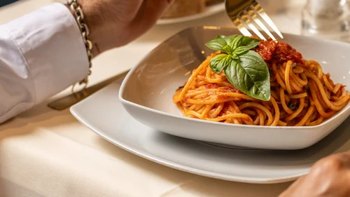 Hotel vicino alla Reggia di Caserta · Regina 4★ Persona che mangia spaghetti al pomodoro con foglia di basilico in piatto bianco
