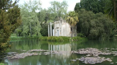 Hotel Regina Caserta · 4 stelle · A due passi dalla Reggia Tempietto antico su un'isola in un lago con ninfee e alberi verdi