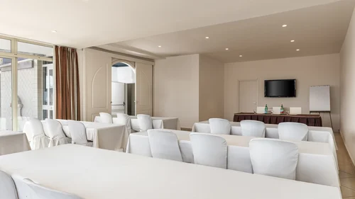 Hotel vicino alla Reggia di Caserta · Regina 4★ Sala conferenze con sedie bianche e tavoli coperti da tovaglie bianche