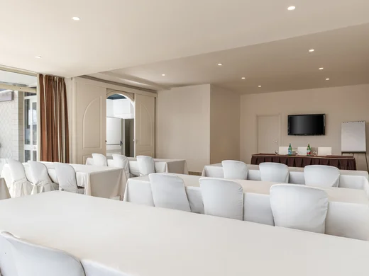Hotel vicino alla Reggia di Caserta · Regina 4★ Sala conferenze con sedie bianche e tavoli coperti da tovaglie bianche