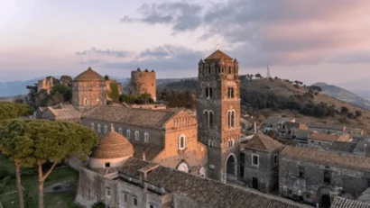 Hotel Regina Caserta · 4 stelle · A due passi dalla Reggia Veduta di un antico complesso di edifici in pietra con torri e cupole al tramonto